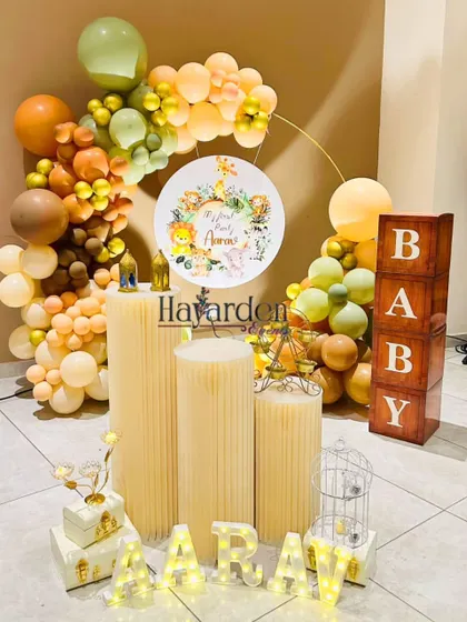 An elegant take on the jungle theme, using a half-ring balloon garland in muted earth tones. The setup includes 'BABY' blocks and light-up letters.