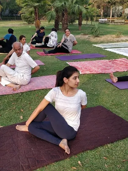 An outdoor yoga class where students of all levels practice together. Here, a younger student and I are both in Ardha Matsyendrasana (Half Lord of the Fishes Pose), a great spinal twist.