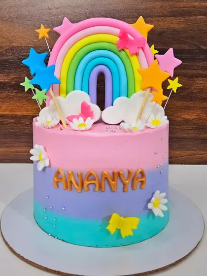 A rainbow and butterfly cake for Ananya's birthday. This chocolate truffle cake is a burst of color, decorated with a fondant rainbow, stars, and butterflies.