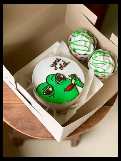 Bring some humor to a birthday with this "You old" meme cake combo. The bento features a funny green character, paired with two cupcakes with matching green drizzle.