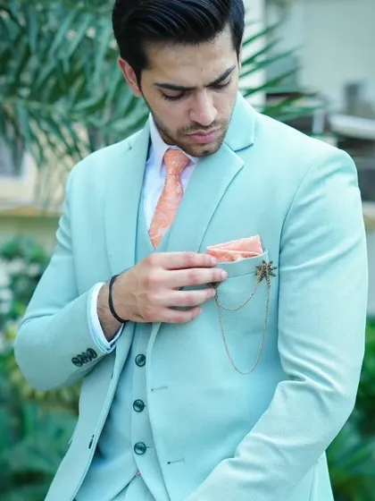 A close-up of the mint green suit, showing the pocket square and chain accessory.