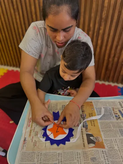 This close-up shot captures the concentration of a mother and child as they carefully place a piece on their craft. These moments of shared focus are invaluable for a child's development.
