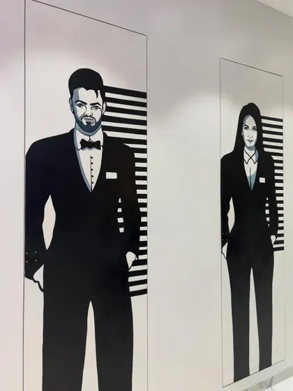 The pair of washroom murals seen together, creating a cohesive and clever design element within the office corridor.