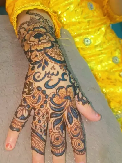 Here you can see the full scope of this detailed party mehendi, extending from the wrist to the fingertips. The bright yellow of her dress makes the dark henna paste stand out beautifully.