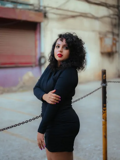 A profile shot of a model in a black dress against an urban background. The focus is on her silhouette and the mood of the city street.