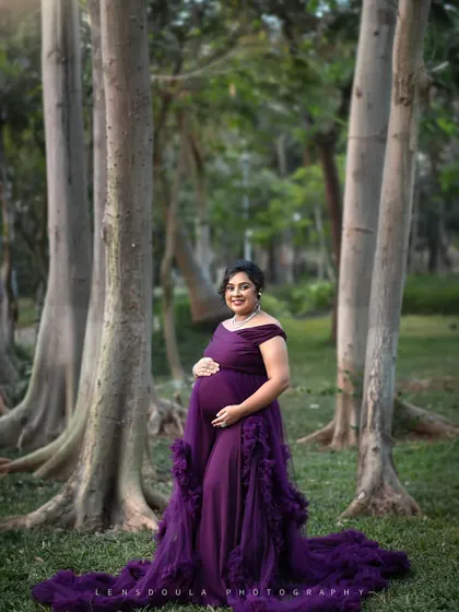 A majestic solo portrait in a beautiful purple gown, standing among the tall trees of a serene forest.