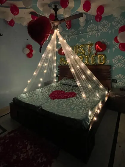 A full view of the 'Just Married' room, with red and white balloons covering the ceiling and a heart of rose petals on the bed.