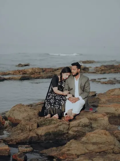 A tender moment on the rocks, with the bride resting her head on the groom's shoulder.