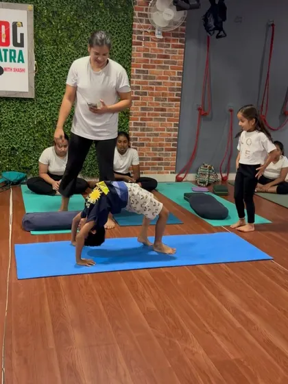 This young boy demonstrates a strong Chakrasana (Wheel Pose), a foundational backbend that builds full-body strength.