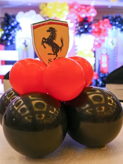 A close-up of a table centerpiece from the Ferrari party, featuring red and black balloons topped with the iconic Ferrari shield.