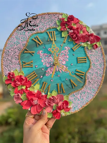 Holding the teal and pink wall clock to showcase its vibrant colors and handcrafted details in natural light.