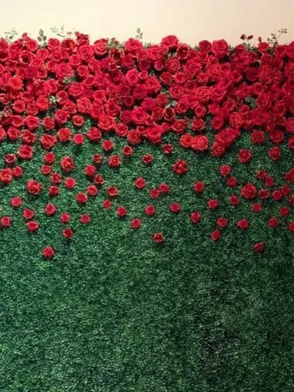 A unique and artistic floral wall design, this piece features red roses appearing to spill down over a lush green backdrop.