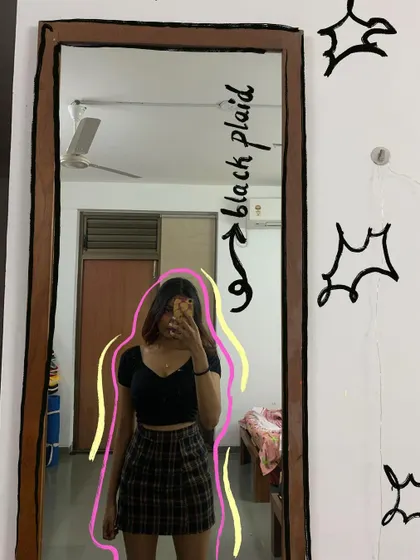 A mirror selfie in a black plaid skirt, with doodles that give it a 90s vibe.