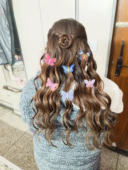 A whimsical open hairstyle with soft waves, decorated with colorful butterfly clips. This is a fun and unique look for a Mehendi or Haldi ceremony.