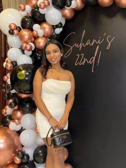 A sleek and stylish setup for Suhani's 22nd birthday. The matte black backdrop with custom calligraphy is framed by a modern balloon arch in rose gold, black, and white.