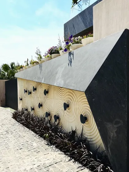 An angled view of the CNC-carved stone wall, showing its three-dimensional quality and the dramatic shadows it creates.