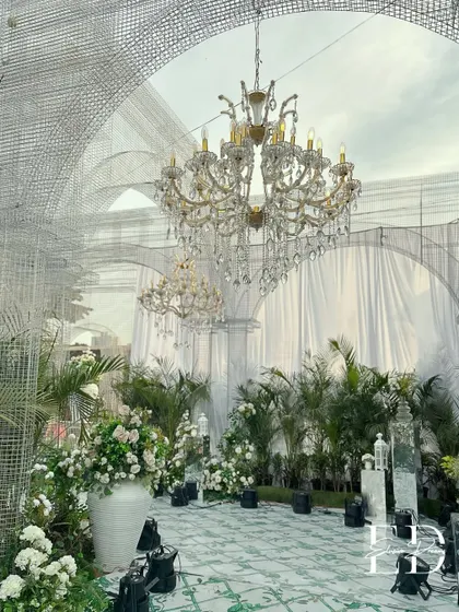A full view of the eco-luxe wedding setup, where grand arches made of wire mesh create a cathedral-like effect over a lush green floor. The design is a masterclass in using sustainable materials to achieve a high-end look.