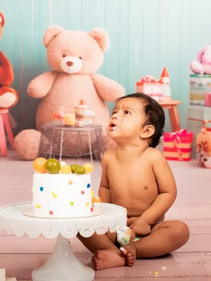 Looking up in wonder. This baby is mesmerized by his first birthday cake, a sweet and innocent moment captured before the smashing fun.