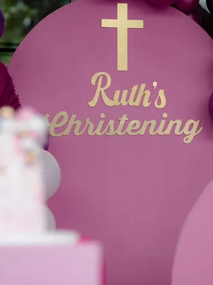 A close-up of the personalized details for Ruth's christening. The gold lettering on the rich magenta backdrop adds a touch of regality to the religious ceremony.