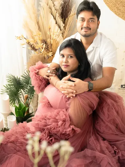 The unforgettable journey of motherhood. This expecting couple shares a loving embrace in a beautifully styled studio setting with a stunning pink ruffled gown.