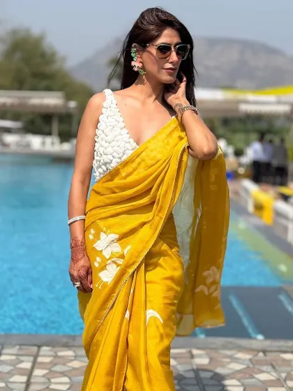 Another look at this stunning hand-painted saree. The combination of the vibrant yellow and the delicate white floral pattern is perfect for summer events. The modern, textured blouse adds a touch of unexpected flair.