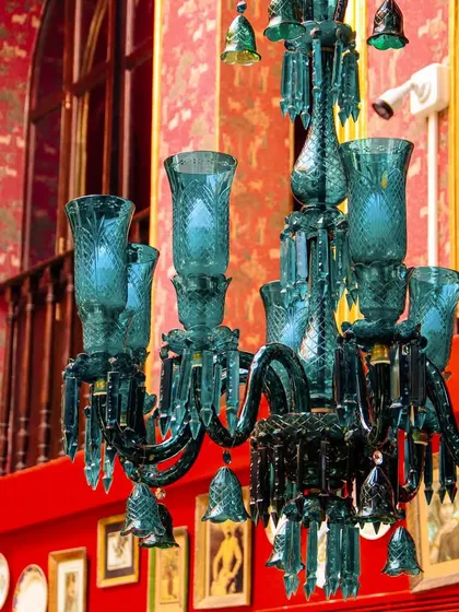 A magnificent blue-green glass chandelier against our signature red walls. These details are essential to the opulent and artful Khubani aesthetic.