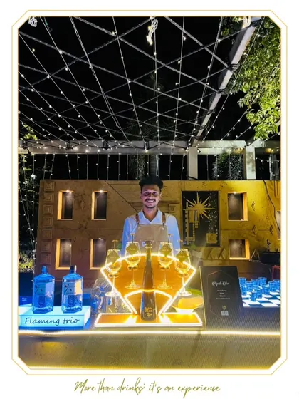 A beautiful outdoor bar setup under a canopy of string lights. Our mixologist stands ready at a premium Tequila Bar, creating an inviting and stylish atmosphere for an evening event.