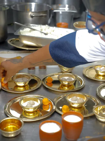 We take great care in plating our dishes, even for large orders. Here, we are preparing individual thalis, ensuring each bowl of Pidi Kozhukatta is perfectly presented before it goes out.