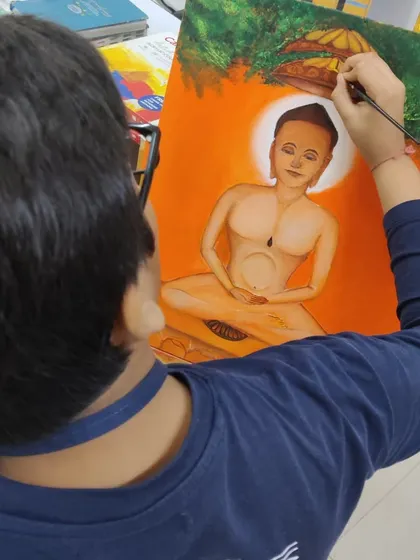 A student carefully paints details on a figure in the Jain art style, using a fine brush for precision. This shows our focus on both broad strokes and intricate work.