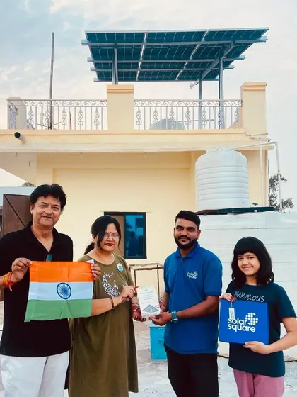 A proud family stands on their rooftop with our team after their solar system is installed. The daughter holds a SolarSquare box, ready to start their journey with clean energy.