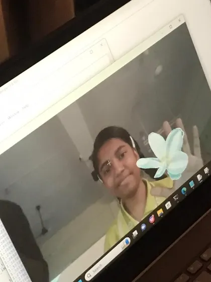 A student smiles as her program successfully applies a virtual flower filter to her face, a fun outcome of our AI workshop.