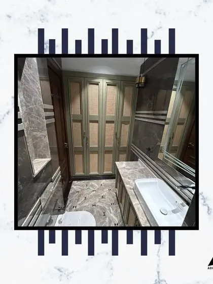 This bathroom combines grey marble walls with stylish green cabinetry, creating a unique and sophisticated look. The long vessel sink adds a modern touch.
