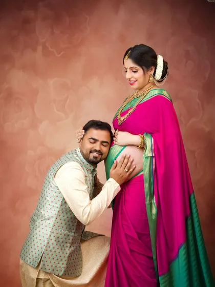 A tender moment as the father-to-be listens to the baby's heartbeat. This is a classic and heartwarming pose that is especially beautiful in traditional attire.