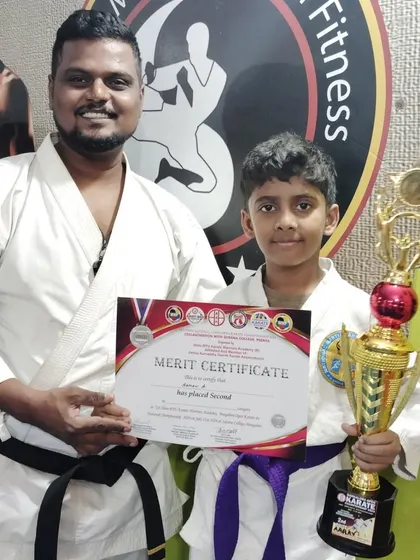 Another second-place winner, this purple belt student proudly displays his karate championship trophy.