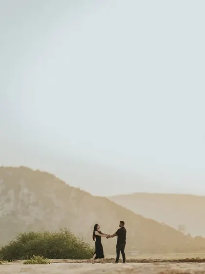 A wide shot of the couple holding hands against the backdrop of a mountain. This image emphasizes the feeling of starting a new journey together in a vast, open landscape.