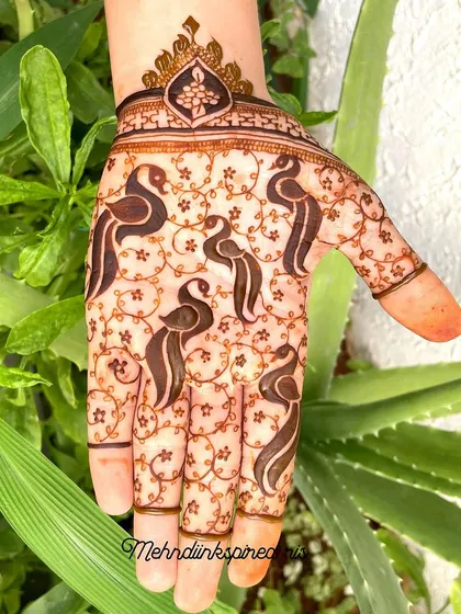 A graceful pattern on the back of the hand featuring stylized bird motifs. The delicate vine work and crowned wristband make this a unique and elegant choice for any occasion.