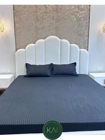 A close-up of the white scalloped headboard, showing the detail of the vertical tufting. This design adds a touch of softness and sophistication to the bedroom, creating a comfortable and stylish backdrop.