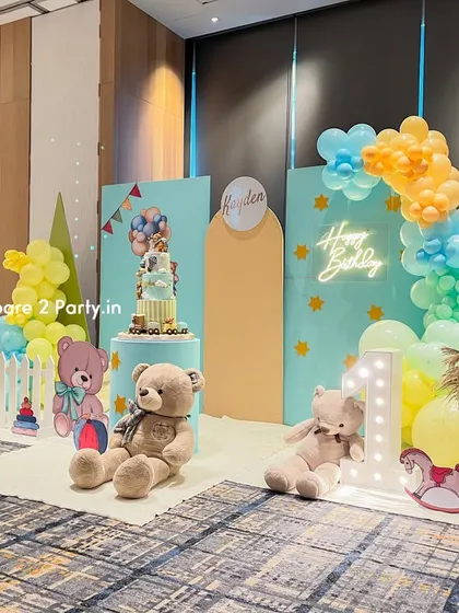 A wide shot of the pastel first birthday party decor, capturing the entire scene with its balanced arrangement of balloons, backdrops, and props.