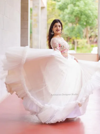 A beautiful action shot of the model twirling in the white lehenga, showing the volume and ruffled hem of the skirt.