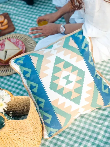 A close-up of our geometric-print cushion cover, adding a pop of color to the classic gingham picnic blanket.
