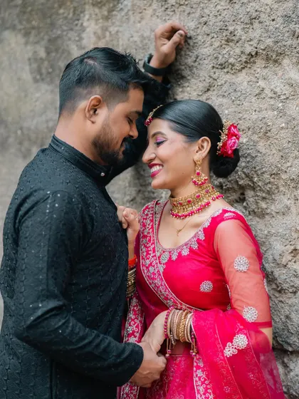 A happy and intimate pre-wedding portrait of a couple leaning against a stone wall, their smiles reflecting their joy.