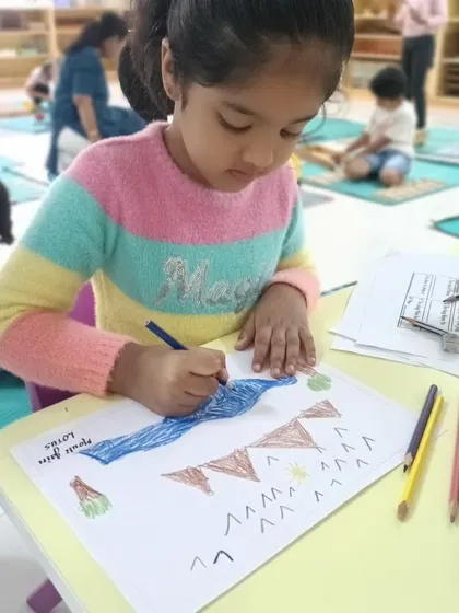 A child draws and colors a map of landforms, an activity that integrates art with geography.