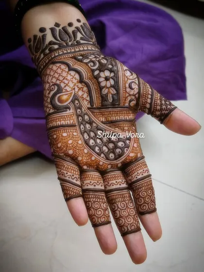 A detailed peacock design covering the palm, showcasing fine feather details and intricate surrounding patterns.