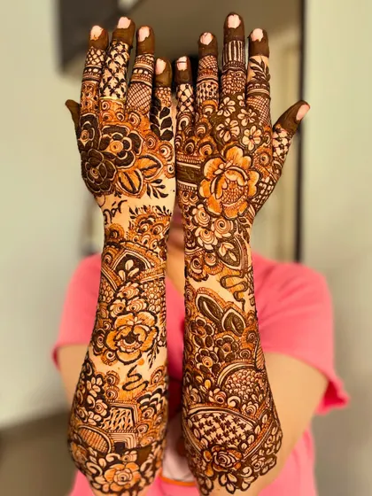 A playful peek-a-boo pose with a stunning floral henna design, perfect for capturing the joy of the occasion.