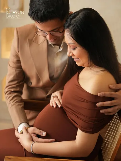 A close up of the couple looking at the baby bump together. His glasses and their focused expression add a sweet, intellectual charm to this loving moment.