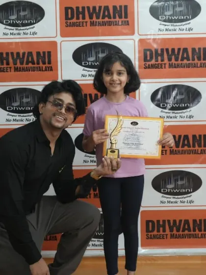 A teacher kneels to present an award to his young student, showing the respect and care in our Guru-Shishya relationships.
