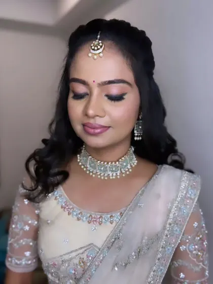 A client looking lovely for her reception in a white lehenga, with her hair in a simple half-up style with soft curls.