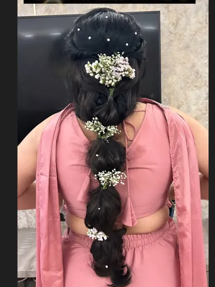 A messy bubble braid decorated with baby's breath and pearls. This is a fun and modern hairstyle, perfect for a bridesmaid or for a sangeet.