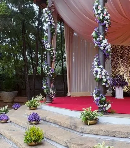 A closer look at the reception stage, with pillars wrapped in spiraling floral garlands and a backdrop wall made entirely of flowers.