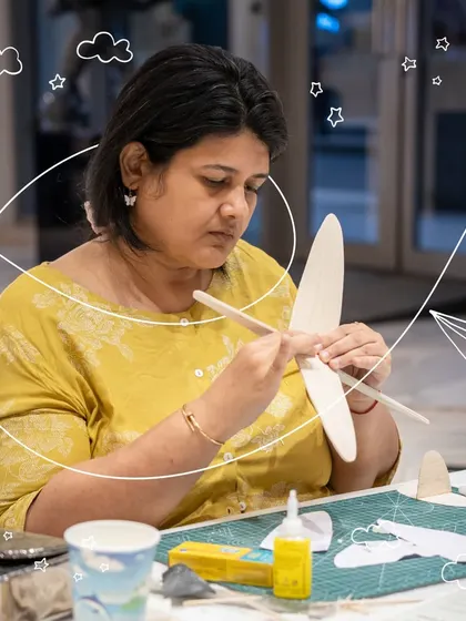 The first step in aviation is understanding the form. Here, a participant carefully assembles the wings of her glider, learning how each component contributes to stable flight. It's a hands-on lesson in aerodynamics and craftsmanship.